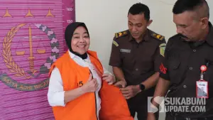 Kades Cikujang Sukabumi Heni Mulyani tersenyum lebar di hadapan kamera saat hendak dibawa ke Lapas Perempuan Bandung. (Sumber Foto: Dok. Kejaksaan)
