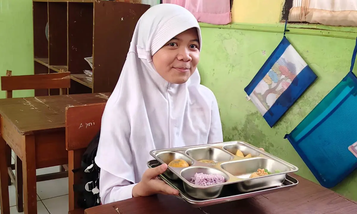Seorang siswa saat memperlihatkan menu nasi ungu dari SPPG  Cikole Cisarua 003, Kota Sukabumi | Foto : Dok. SPPG
