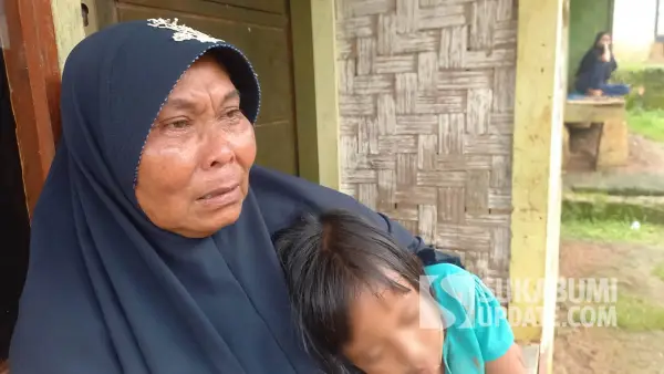 Sambil memeluk cucunya, Aminah (50 tahun), warga Ciracap Sukabumi, menangis saat menceritakan anak dan menantunya ditahan polisi karena kasus perburuan babi hutan menggunakan senjata rakitan. (Sumber Foto: SU/Ragil Gilang)