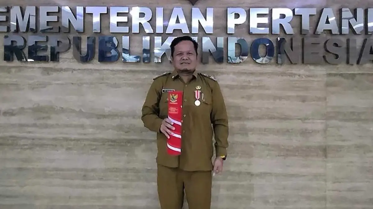 Kepala Dinas Pertanian Kabupaten Sukabumi, H. Aep Majmudin, menunjukkan penghargaan dari Mentan RI atas kontribusi dalam mendukung Program Swasembada Pangan Nasional.