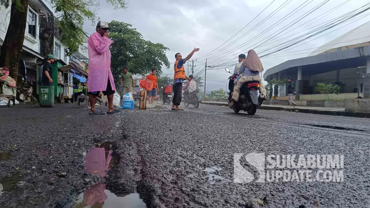 Kondisi jalan nasional yang berlubang di depan Alun-alun Gadobangkong, Palabuhanratu, Kabupaten Sukabumi saat ditambal warga.