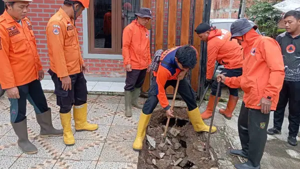 TPT drainase di Jalan Soka Gunungpuyuh jebol dan menyebabkan halaman rumah warga amblas. BPBD Kota Sukabumi bergerak cepat melakukan penanganan darurat dengan bantuan material semen dan karung. (Sumber Foto: Dok. BPBD)