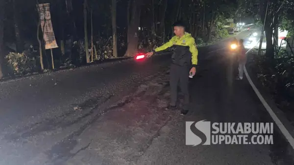 Petugas kepolisian memeriksa kondisi jalan rusak di Jalan Nasional Cisolok–Palabuhanratu, Cikakak, Sukabumi, usai kecelakaan tunggal yang melukai seorang pengendara motor. (Sumber Foto: Dok. Polres Sukabumi)