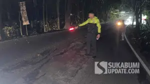 Petugas kepolisian memeriksa kondisi jalan rusak di Jalan Nasional Cisolok–Palabuhanratu, Cikakak, Sukabumi, usai kecelakaan tunggal yang melukai seorang pengendara motor. (Sumber Foto: Dok. Polres Sukabumi)