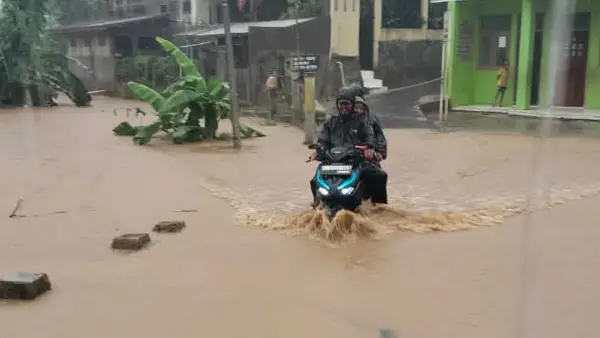 Warga saat melintasi jalan lingkungan yang terendam banjir luapan Sungai Cibaregbeg Cicurug Sukabumi, Minggu (24/5/2026). (Sumber Foto: Istimewa)