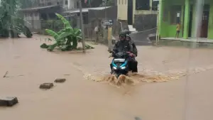Warga saat melintasi jalan lingkungan yang terendam banjir luapan Sungai Cibaregbeg Cicurug Sukabumi, Minggu (24/5/2026). (Sumber Foto: Istimewa)