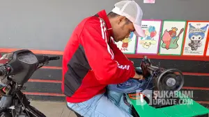 Iwan saat memperbaiki celana jeans milik pelanggan. (Sumber : SU/Ragil Gilang).