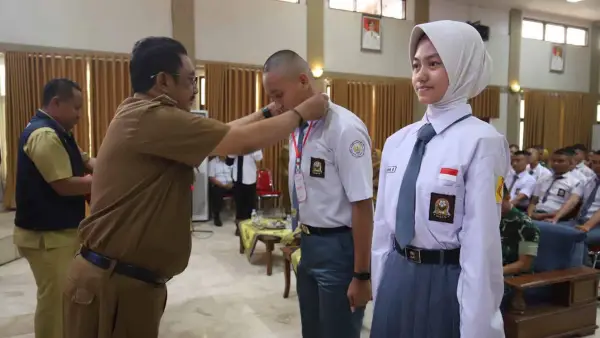 Bupati Asep Japar menyematkan tanda peserta kepada calon anggota Paskibraka Kabupaten Sukabumi saat pembukaan Diklat Paskibraka Tahun 2026. (Sumber: Diskominfosan Kab. Sukabumi)