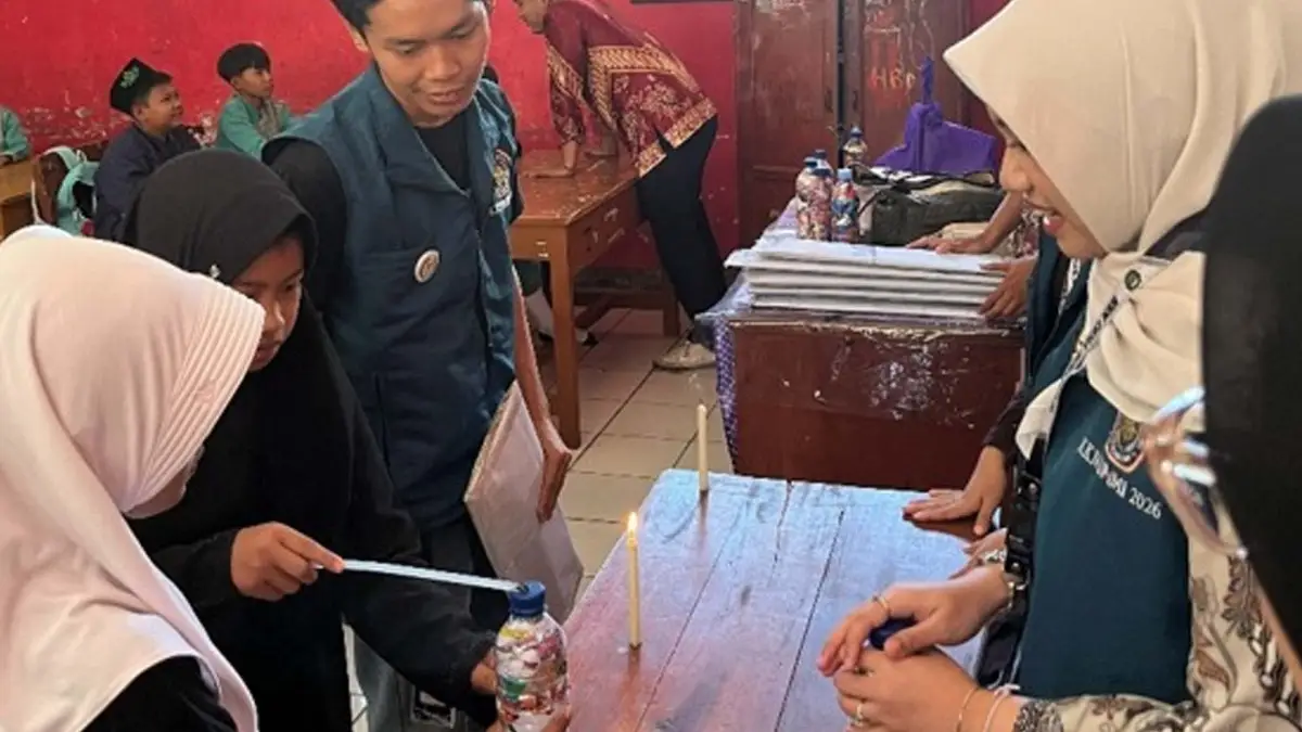 Mahasiswa KKN mendampingi siswa SDN Sukaharja saat praktik pembuatan ecobrick dengan memadatkan sampah plastik ke dalam botol bekas.