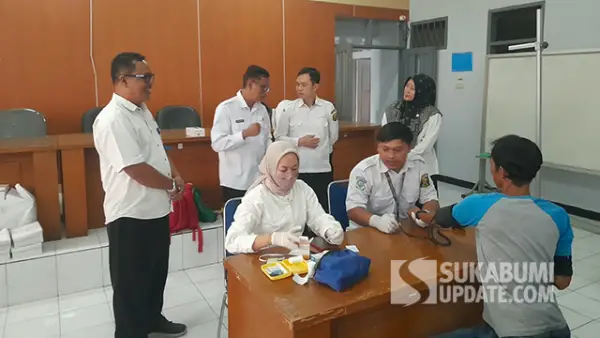 Petugas UPTD Puskesmas Cisaat saat cek kesehatan 15 warga Kabupaten Sukabumi yang baru tiba setelah dipulangkan dari Kalimantan Utara, di Kantor Dinas Sosial Kabupaten Sukabumi, Rabu (19/8/2026). (Sumber : SU/Ibnu Sanubari)
