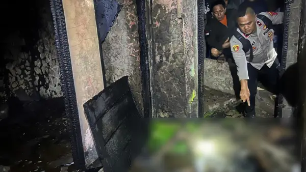 Polisi saat menunjukan jenazah korban di dalam bangunan yang terbakar. (Sumber: Istimewa)