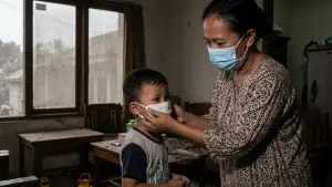 Ilustrasi orang tua melindungi anaknya dari paparan abu vulkanik melalui pemasangan masker. (Sumber Foto: AI)