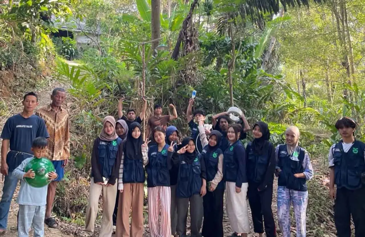 Mahasiswa KKN berfoto bersama warga jelang pemasangan lampu penerangan jalan.