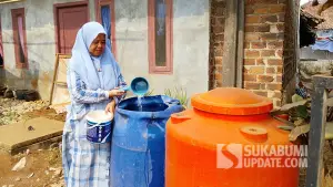 Emal Lesmanawati warga Kampung Legok Nyenang, Desa Cikujang, Kecamatan Gunungguruh, Kabupaten Sukabumi yang terserang diare saat menunjukkan toren tampungan air di depan rumahnya. (Sumber : SU/Asep Awaludin).